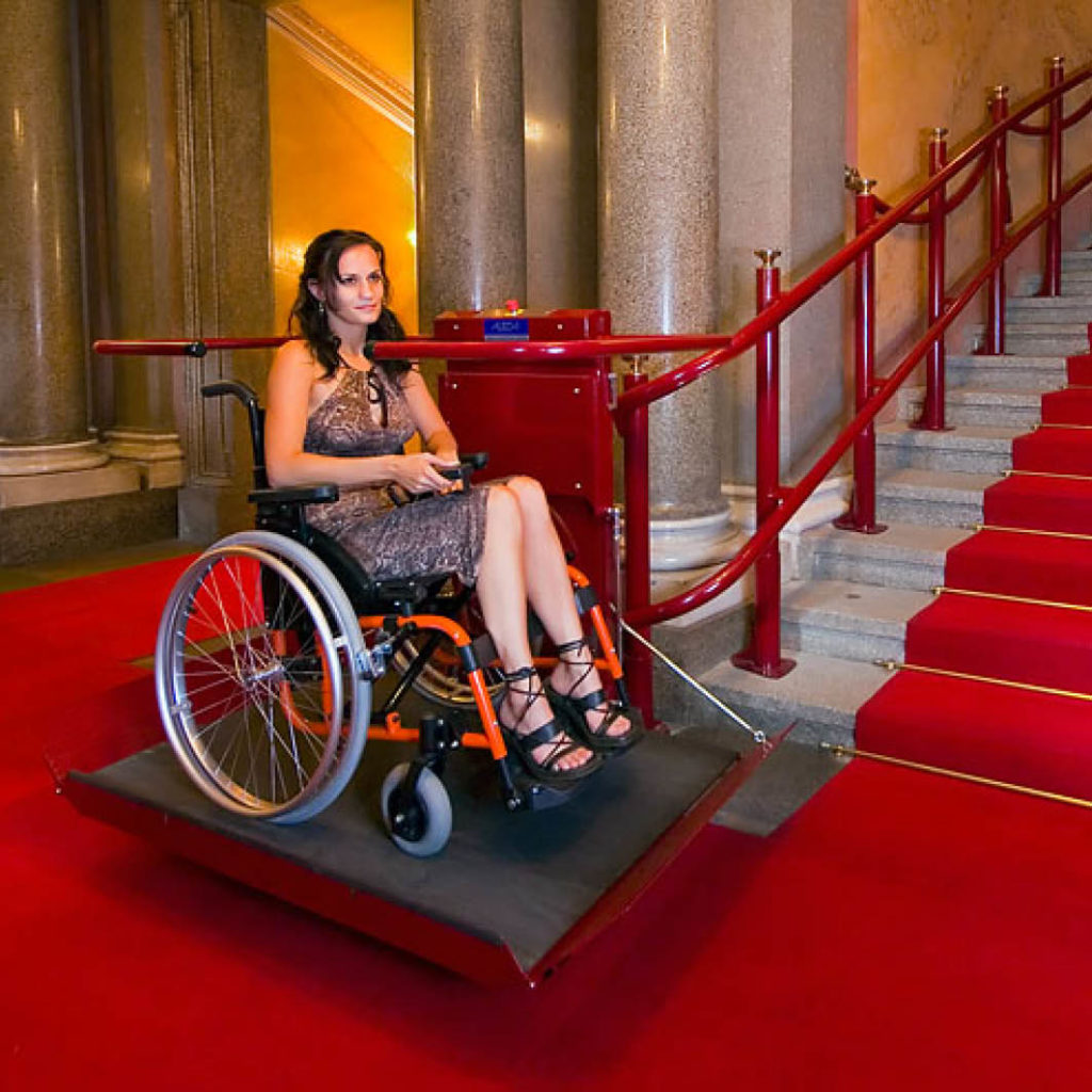 Plattformlift Omega mit einer Frau im Rollstuhl montiert auf einer langen Treppe