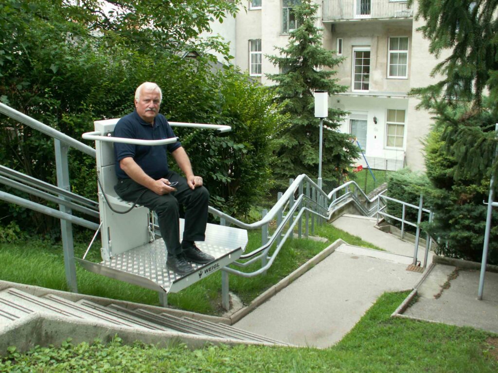 Rollstuhllift Omega in weiss im Aussenbereich auf einer langen Treppe montiert