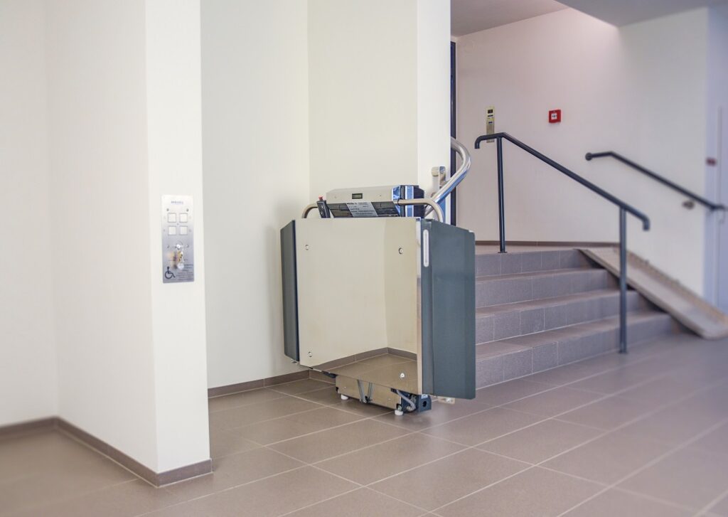 Treppenlift Rollstuhl Stratos neben einer geraden Treppe im Innenbereich